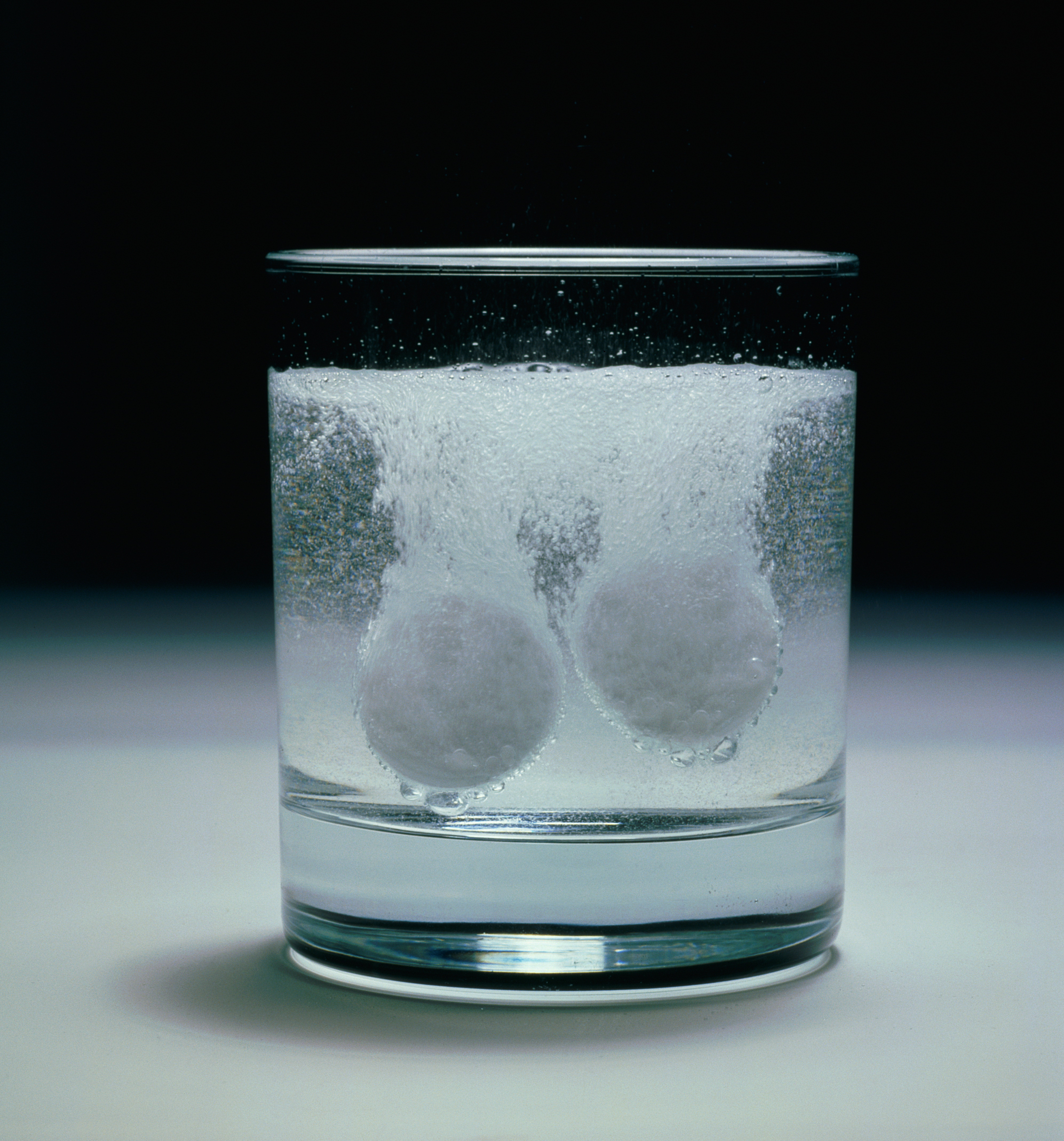 Two soluble tablets in glass dissolving in water