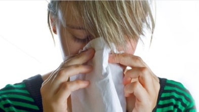 A woman using a tissue to blow her nose