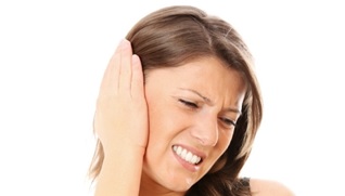 A woman holding her hand to her ear and frowning in pain