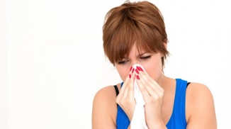 A woman holding a tissue to her nose