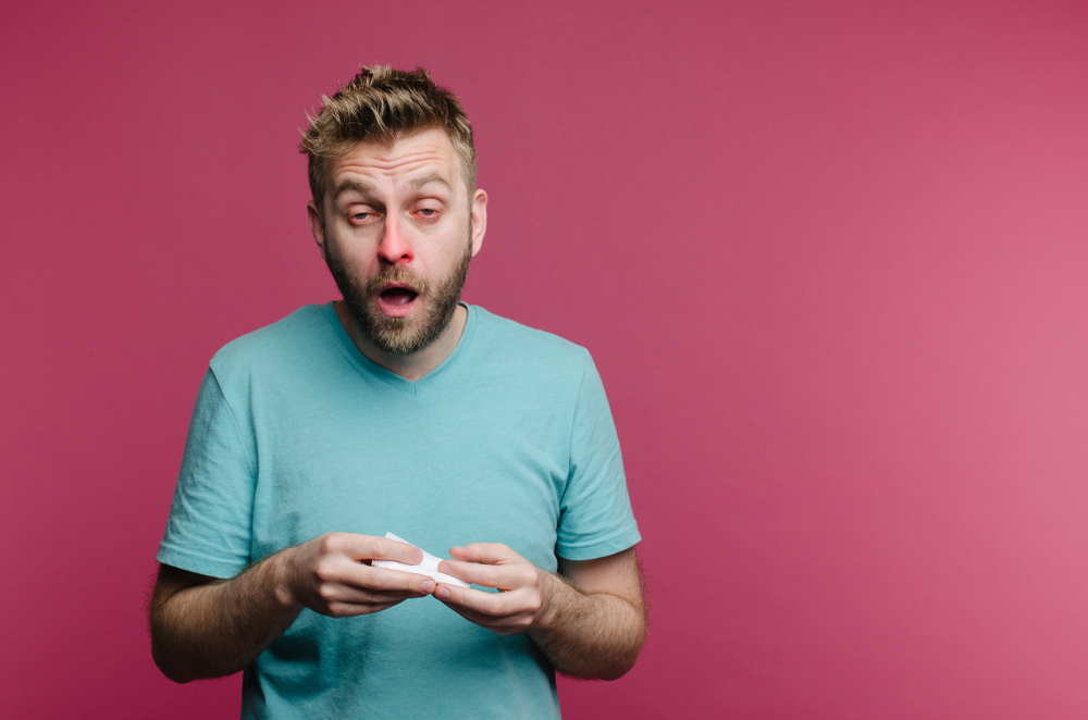 studio picture of a young man with handkerchief going to sneeze. Sick guy isolated has runny nose. man makes a cure for the common cold from the air conditioner

