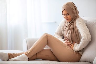 Young muslim woman feeling stomach ache, suffering from gastritis problem. Muslim woman with stomach ache, menstrual period cramp, abdominal pain, food poisoning