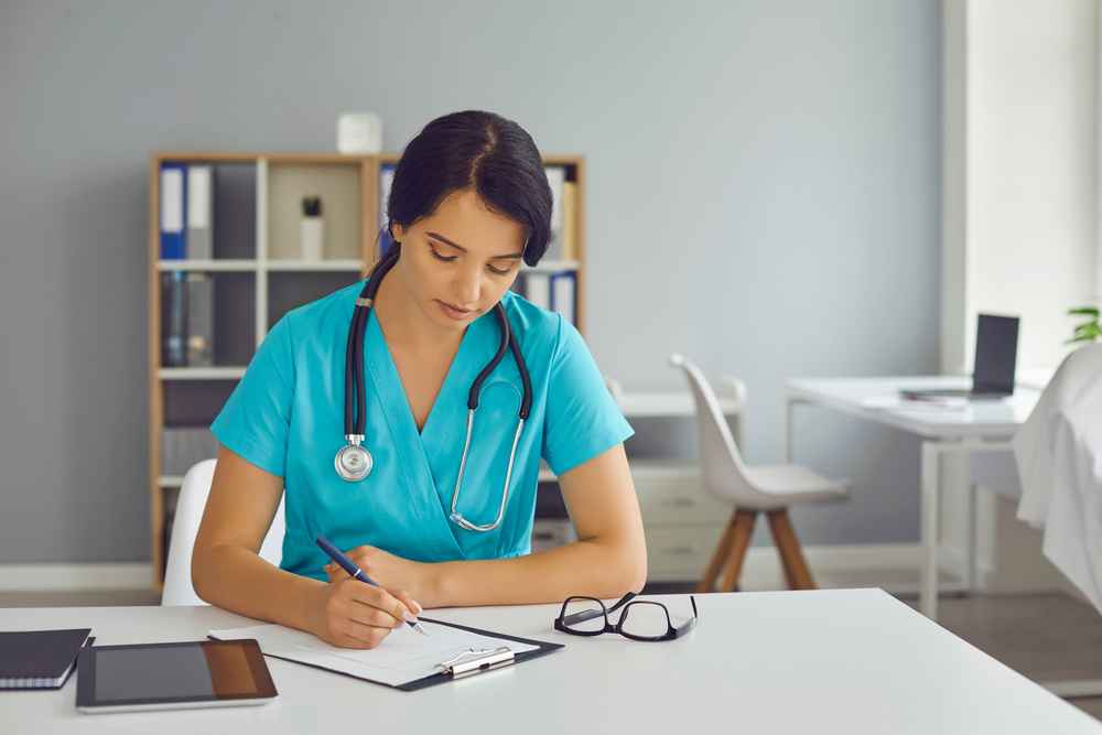 Female physician working alone in hospital office doing paperwork