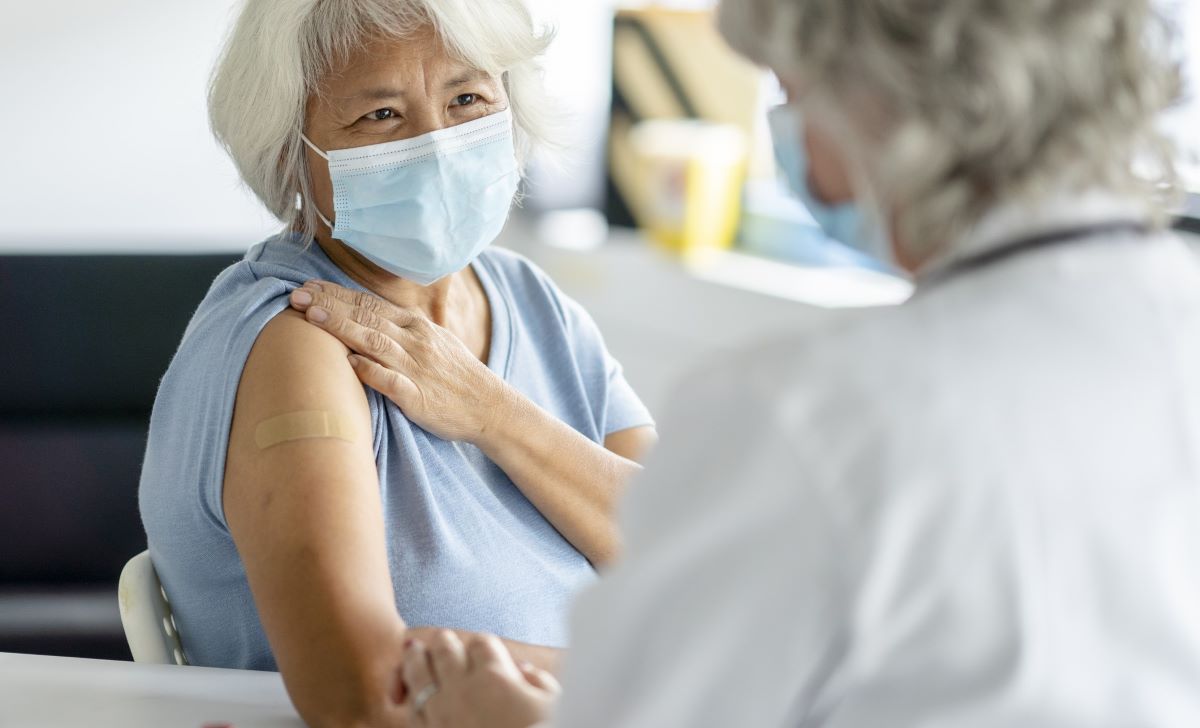 Elderly female holding sleeve up for injection