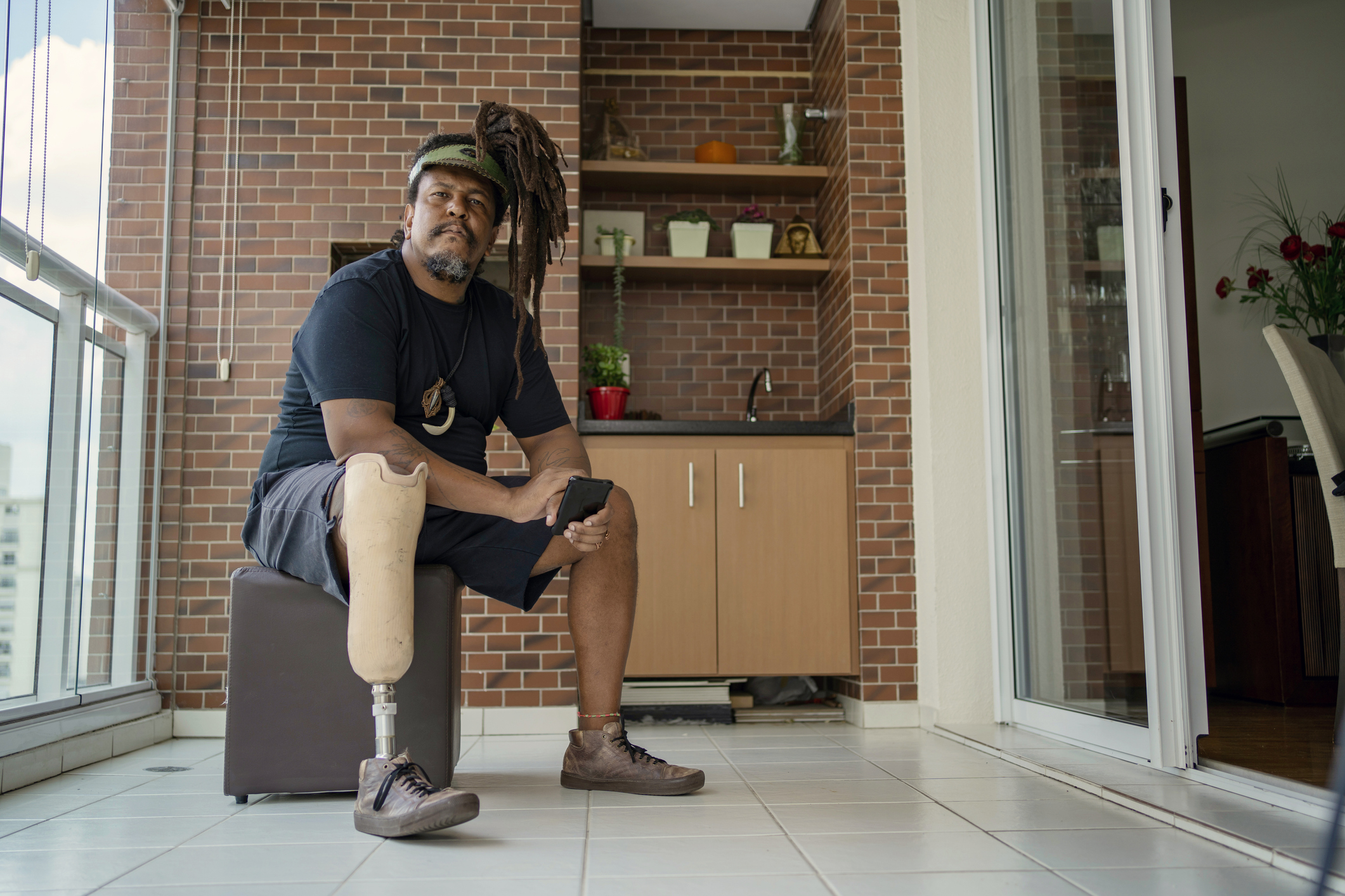 Portrait of man with leg prosthesis using smart phone at home